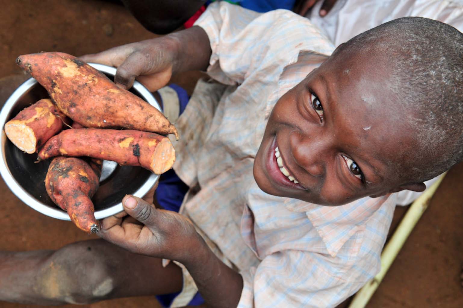 A child hold a bowl of orange-fleshed sweet potatoes in Tanzania. Pic by Neil Palmer (CIAT).